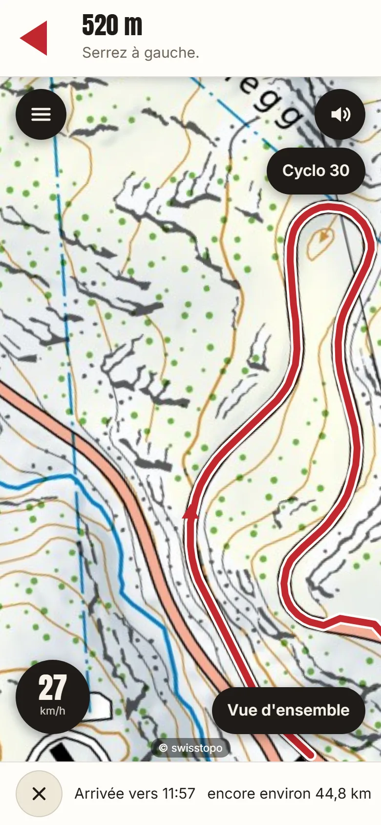 Le navigateur sur le téléphone dans la montée du Grimsel : en haut 520 m avant de tourner légèrement à gauche, l'itinéraire rouge sur la carte nationale, en bas 27 km/h et l'heure d'arrivée.