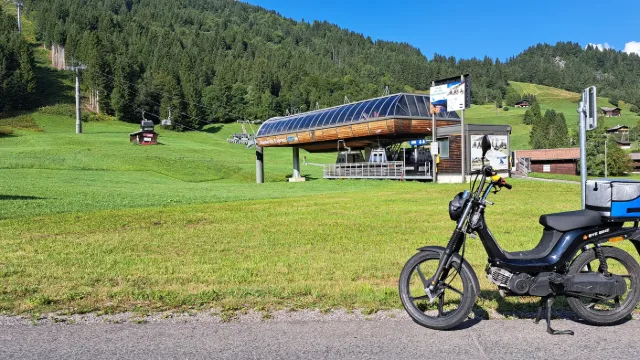 Un motorino su un prato davanti a una stazione di risalita.