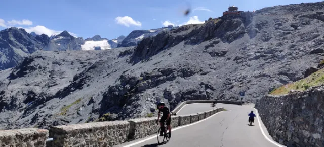 Un motociclista lungo il muretto del passo.