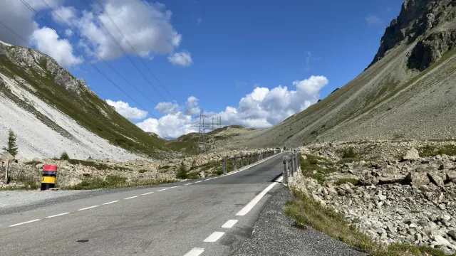 Una strada di passo attraverso un'ampia valle d'alta quota.