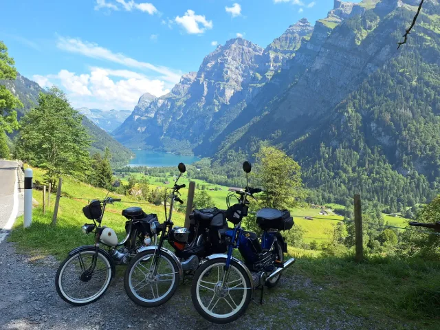 Motorini sopra un lago alpino tra le pareti rocciose.