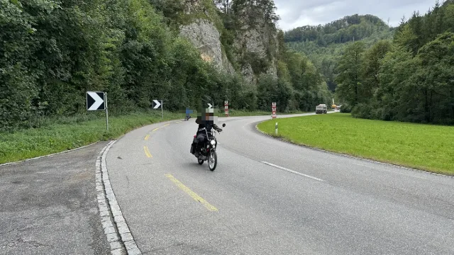 Ein Töfflifahrer in einer Kurve unter Felsen.