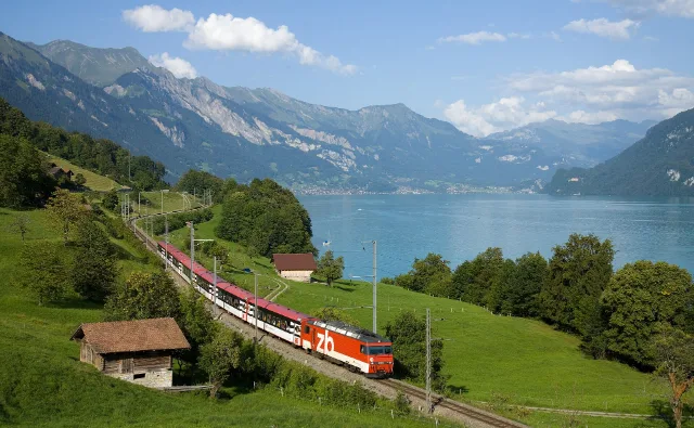 Ein Zug am Brienzersee, dahinter die Berge.