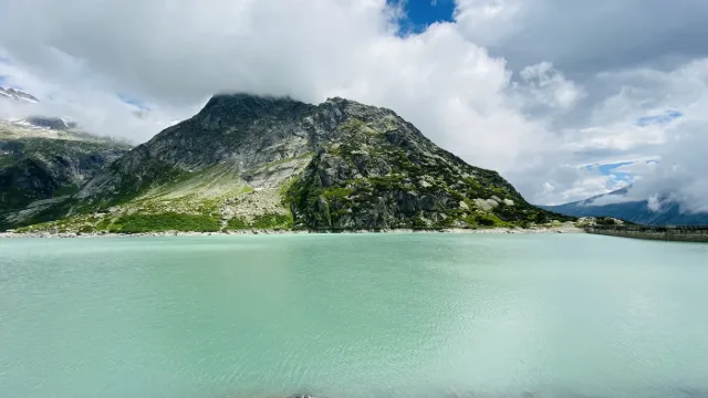 Ein türkiser Stausee unter Bergen.